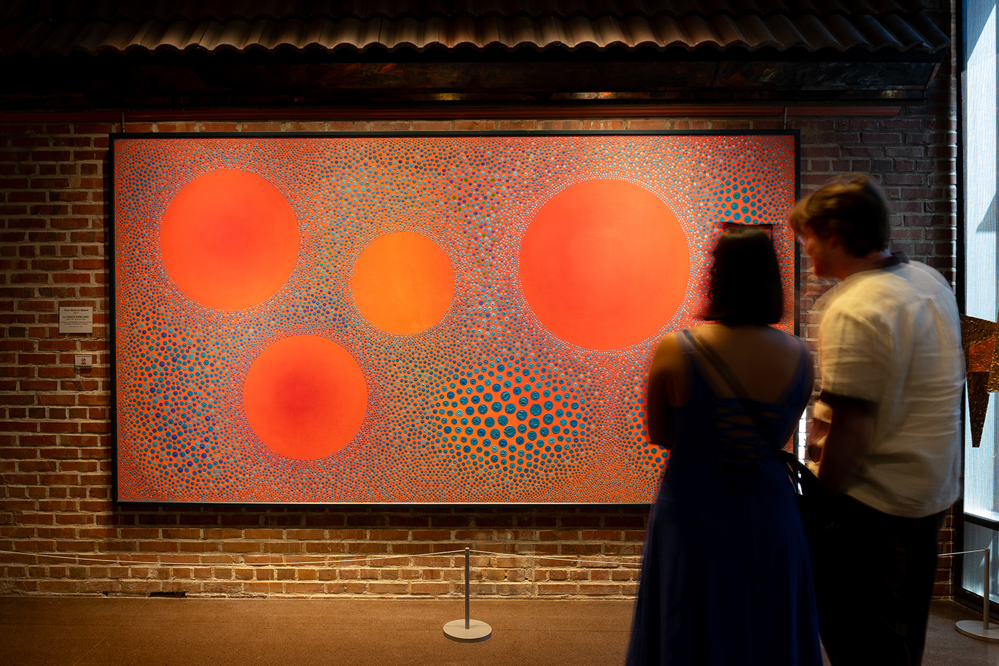 Couple looking at an abstract dot painting by Vance Kirkland