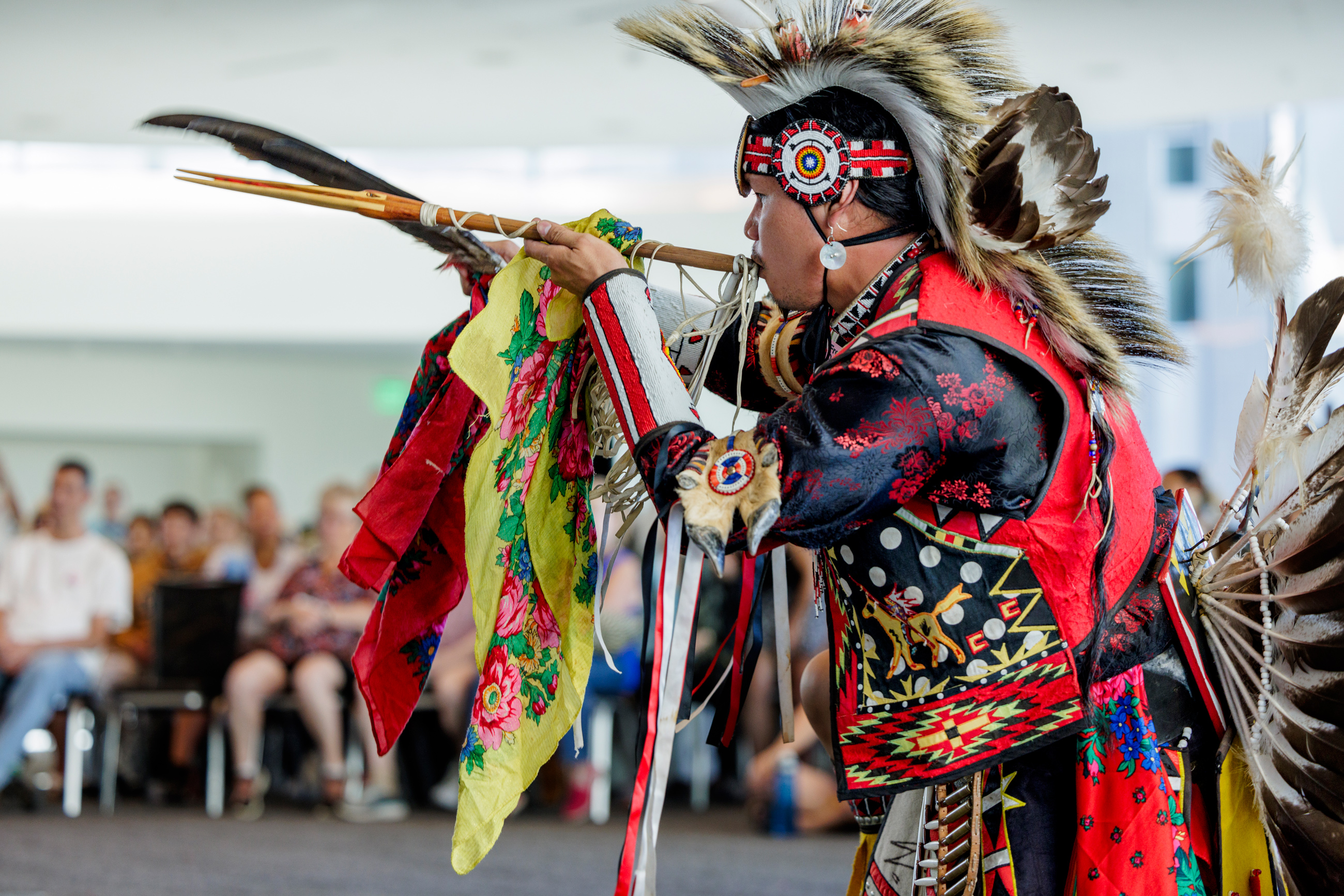 Man performing with a flute while dressed in traditional Native American wear