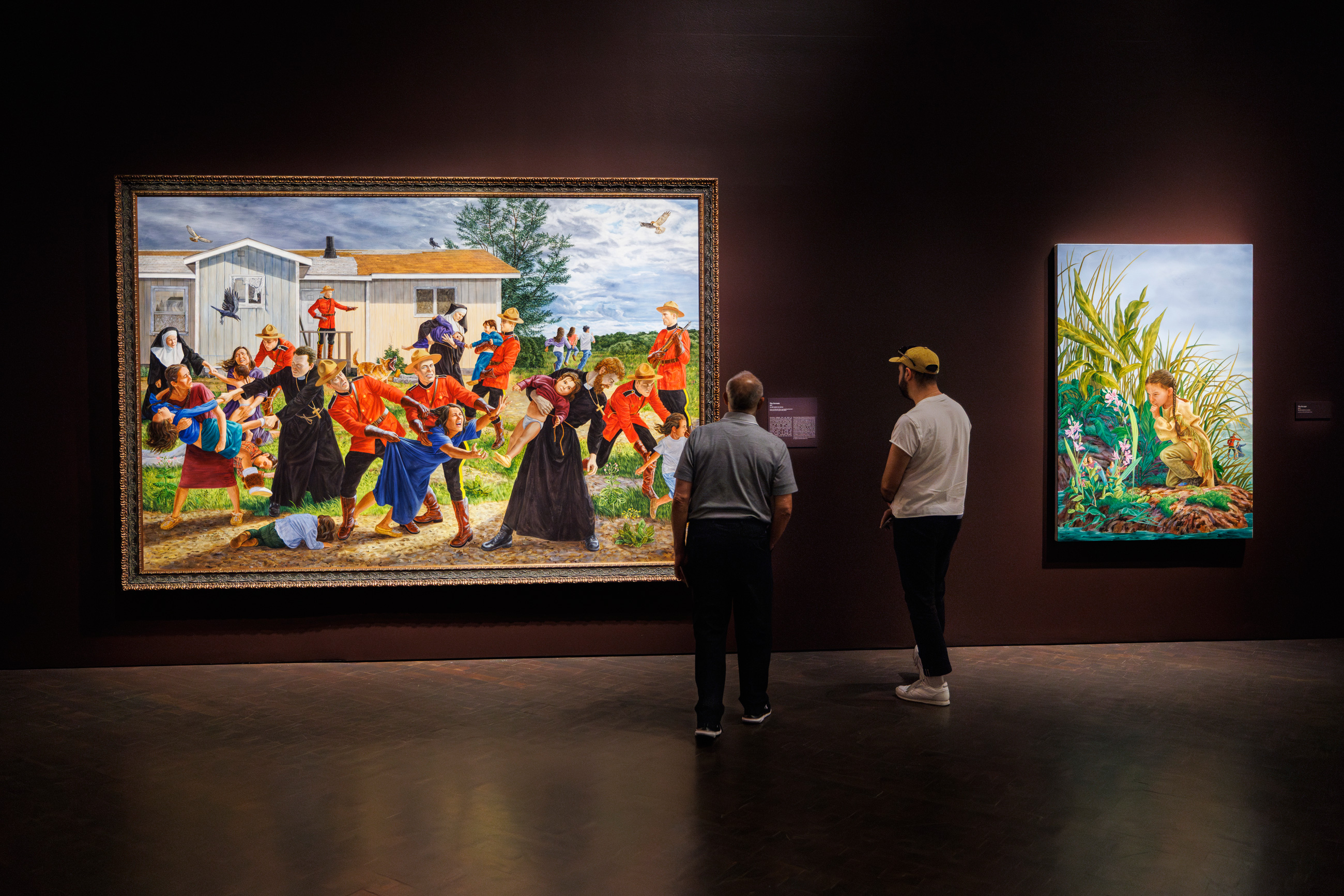 two people looking at paintings in the exhibition