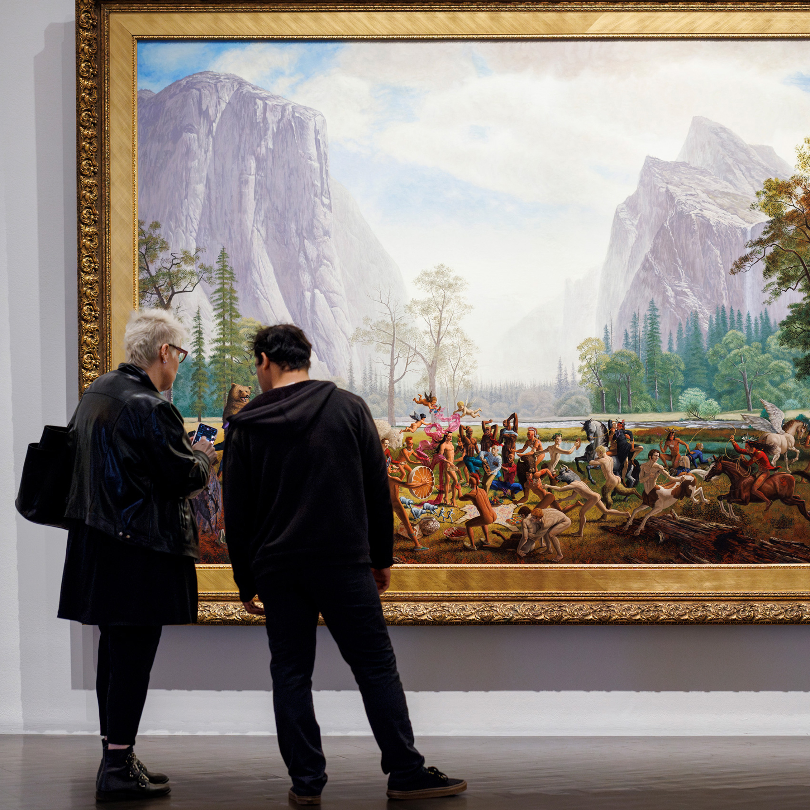 2 people looking at a large painting in the Monkman exhibition