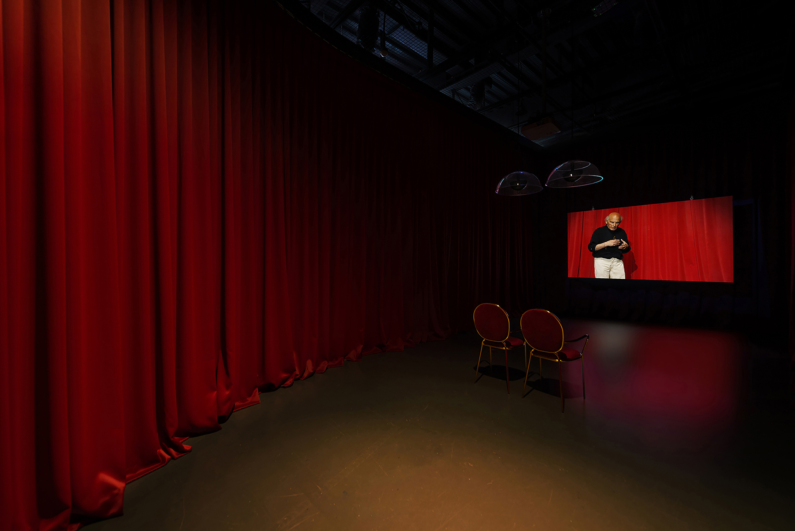 Projection screen in a red-curtained room with two chairs