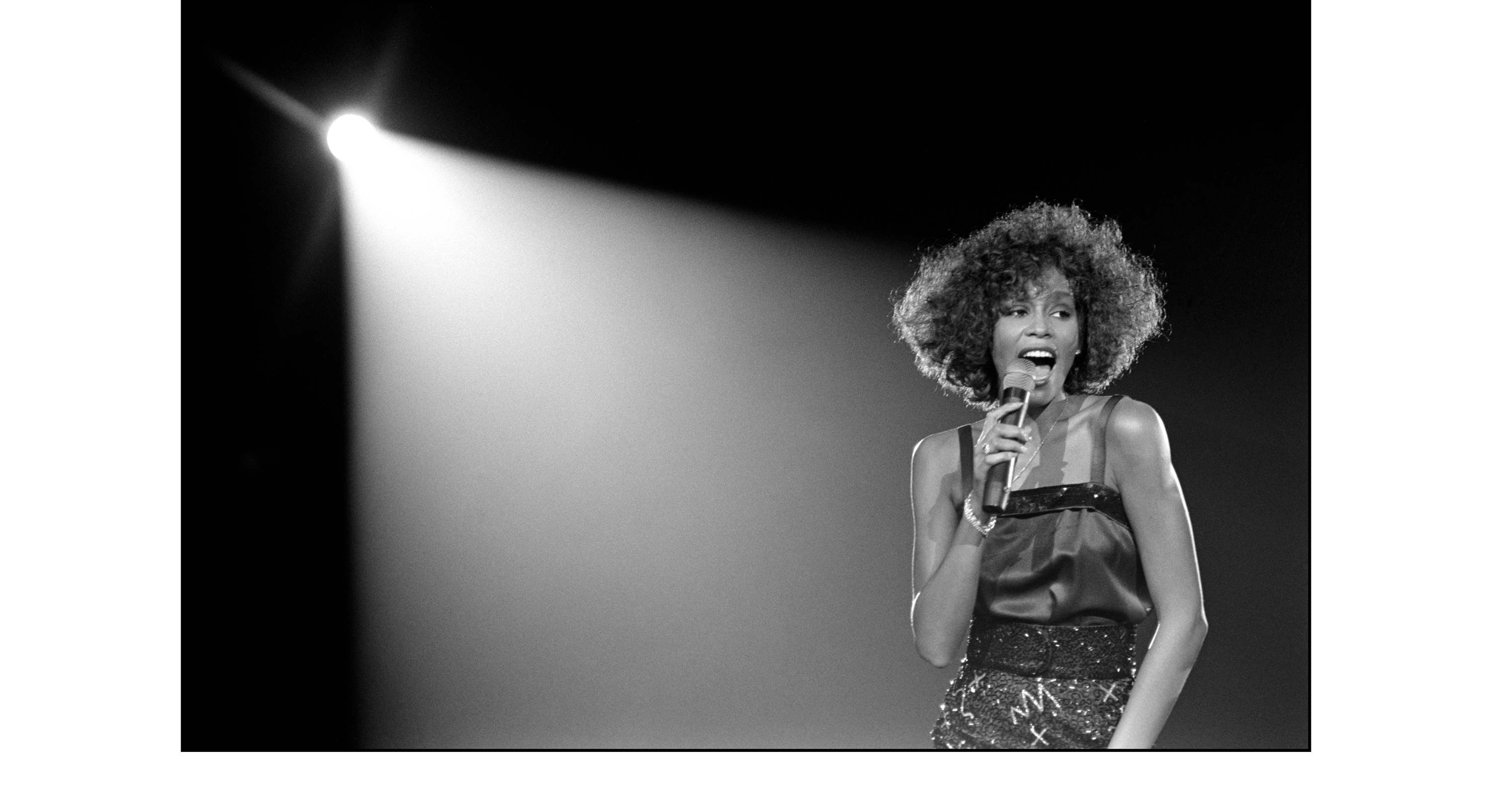 Black and white photograph of Whitney Houston performing on stage