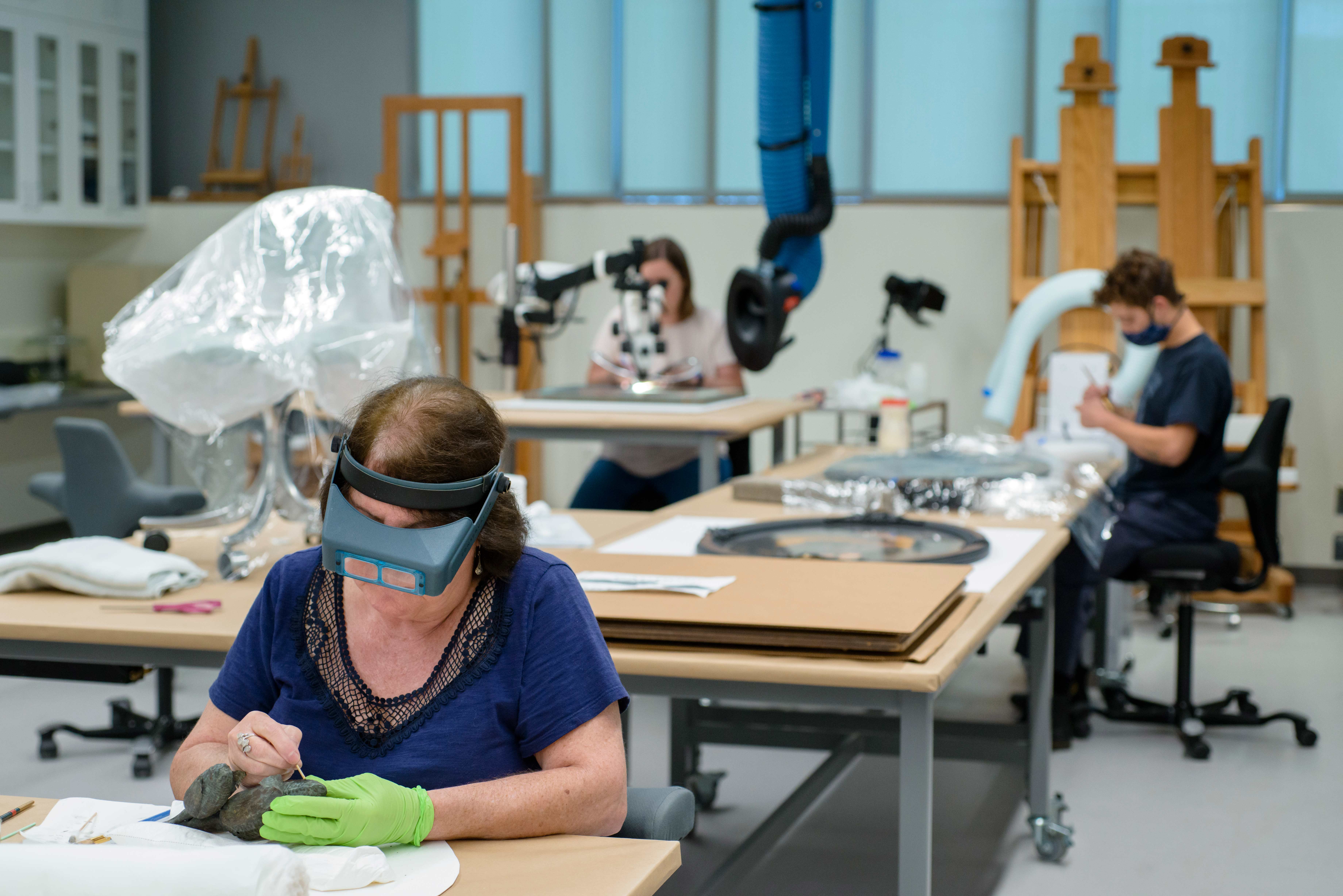 Woman in headgear working in the museum conservation lab