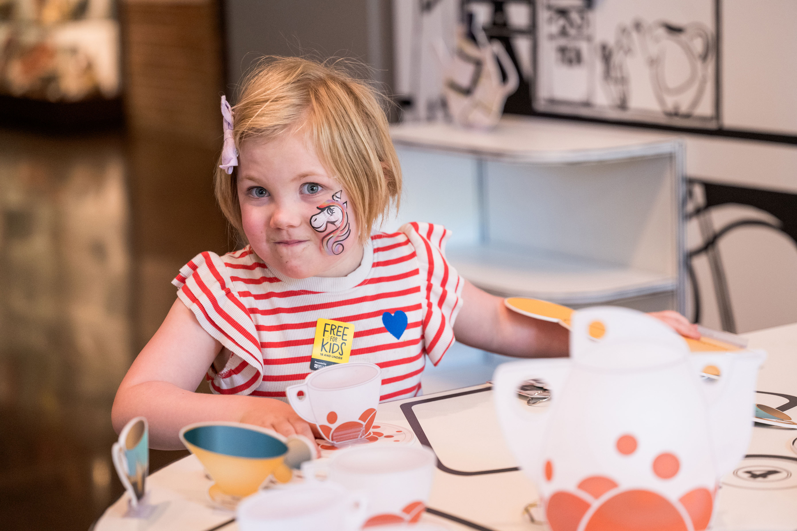 Young girl with a unicorn face painting smiling at the camera