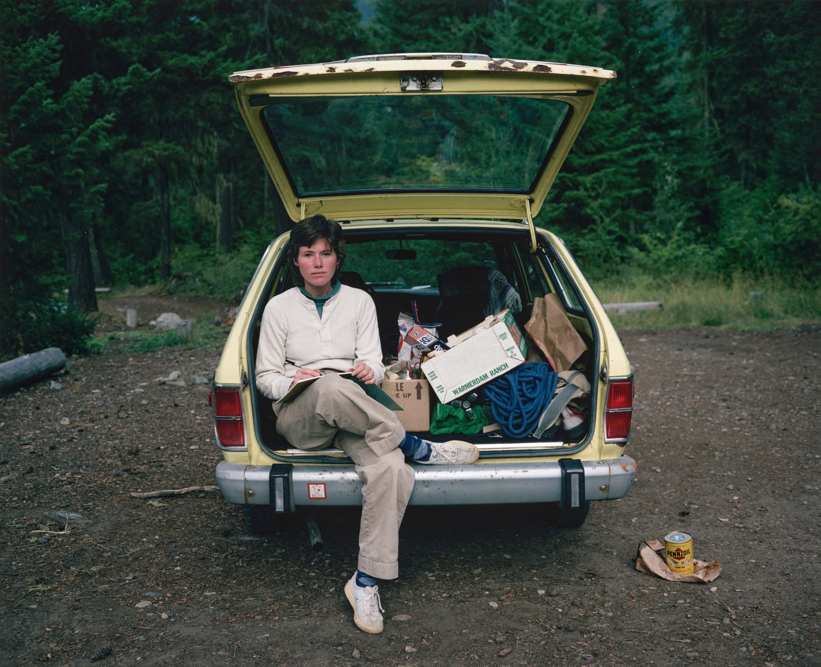 Woman sitting in the back of a car that's filled top-to-bottom with belongings