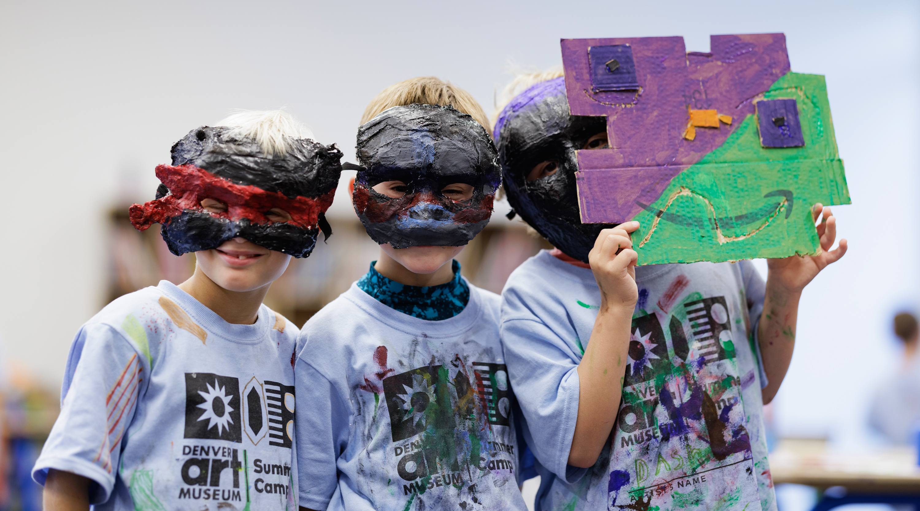 Three young boys playfully wearing masks