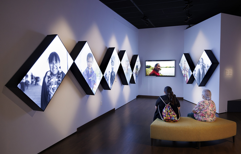 Two visitors looking at a row of screens