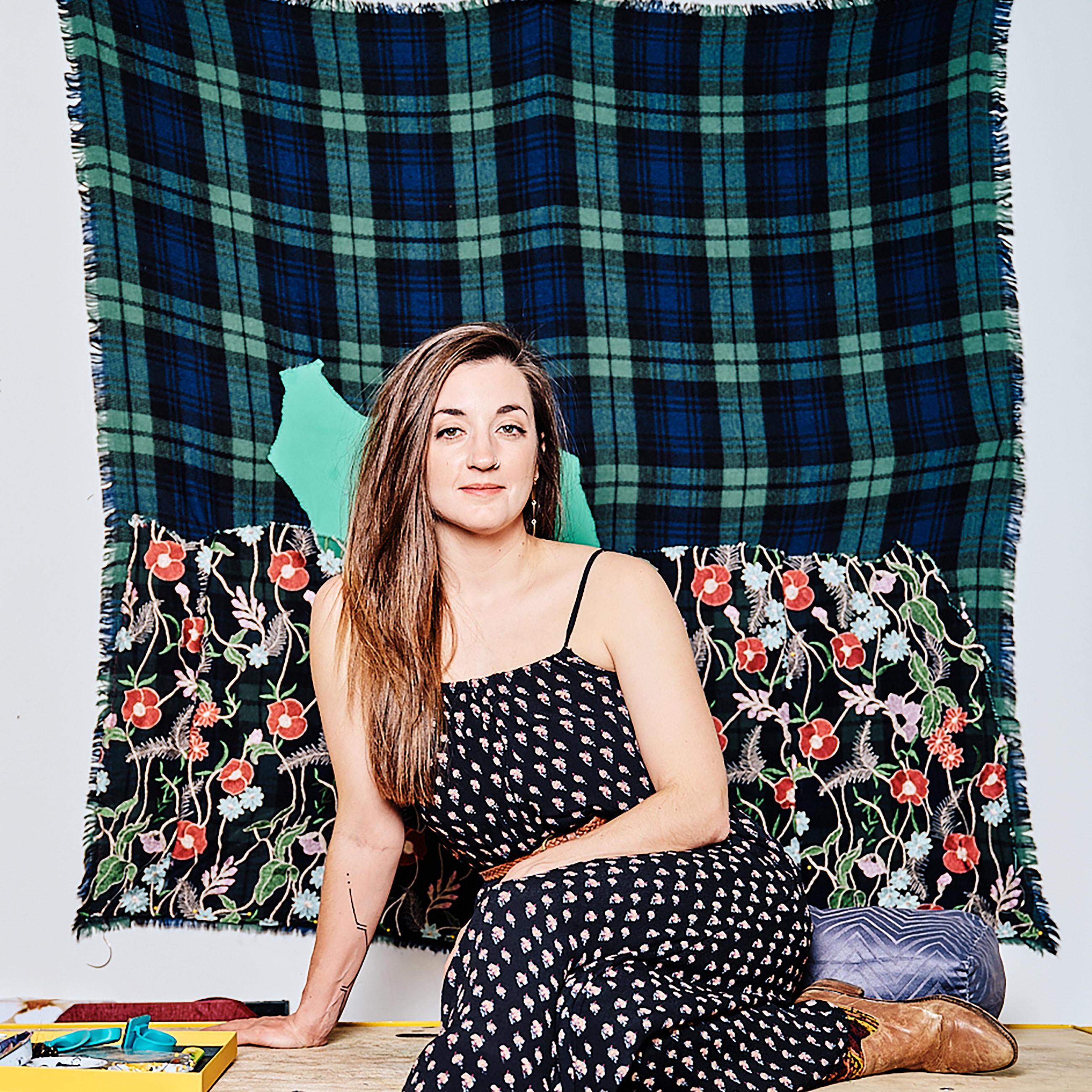 woman sitting on a bench in front of a textile wall hanging