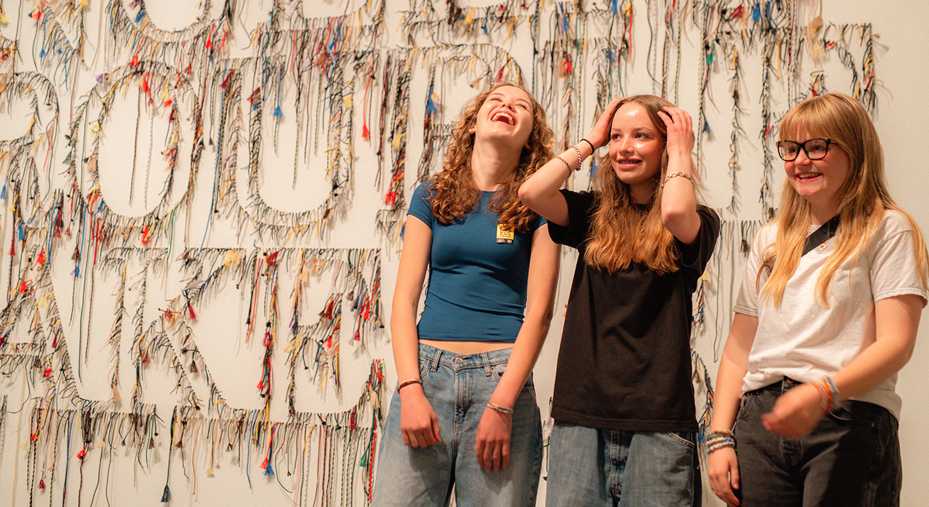 Three teens posing in front of the "angelic troublemakers" artwork