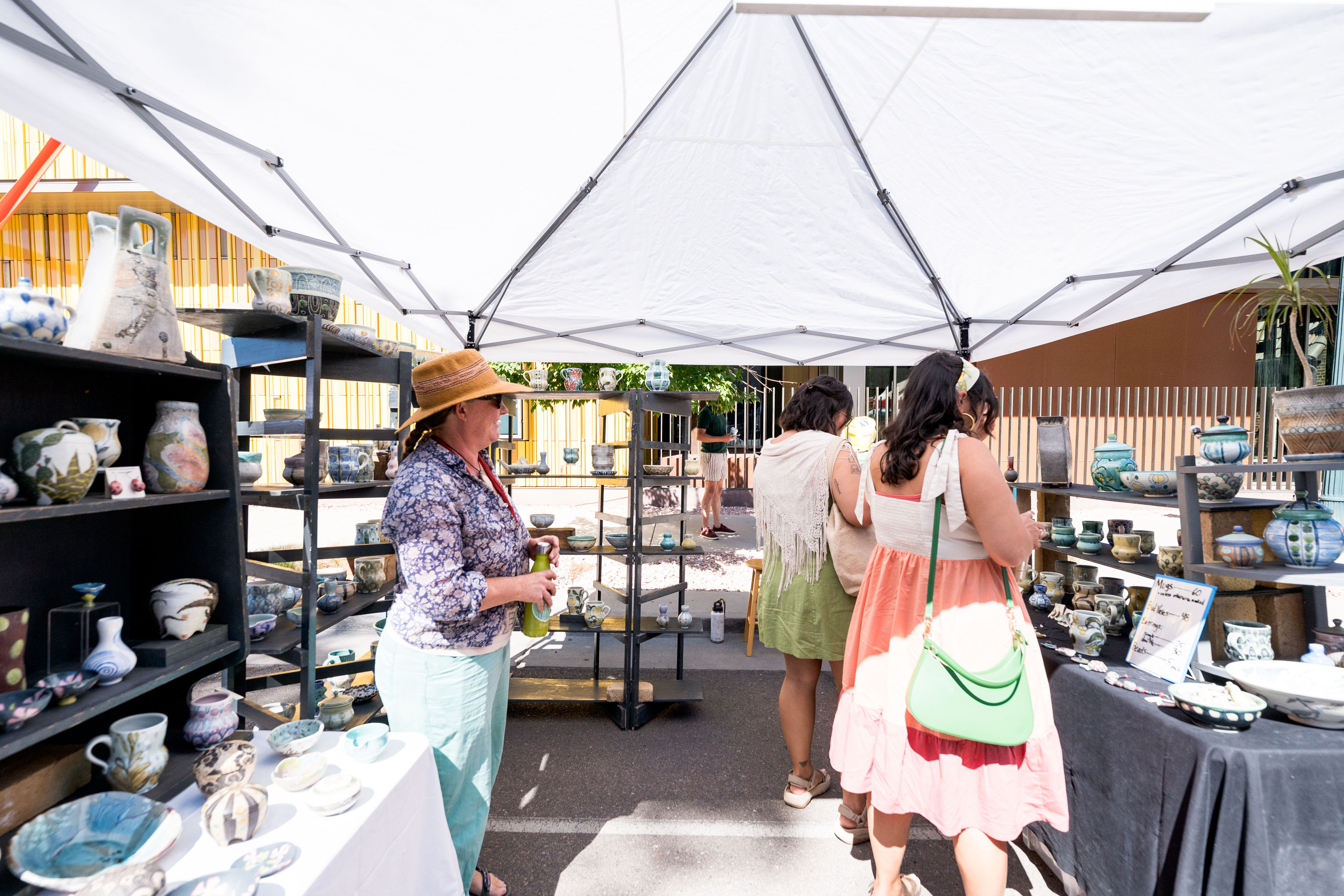 Two visitors shop at ceramic artist Sarah Christensen's booth during a festival at the Denver Art Museum.