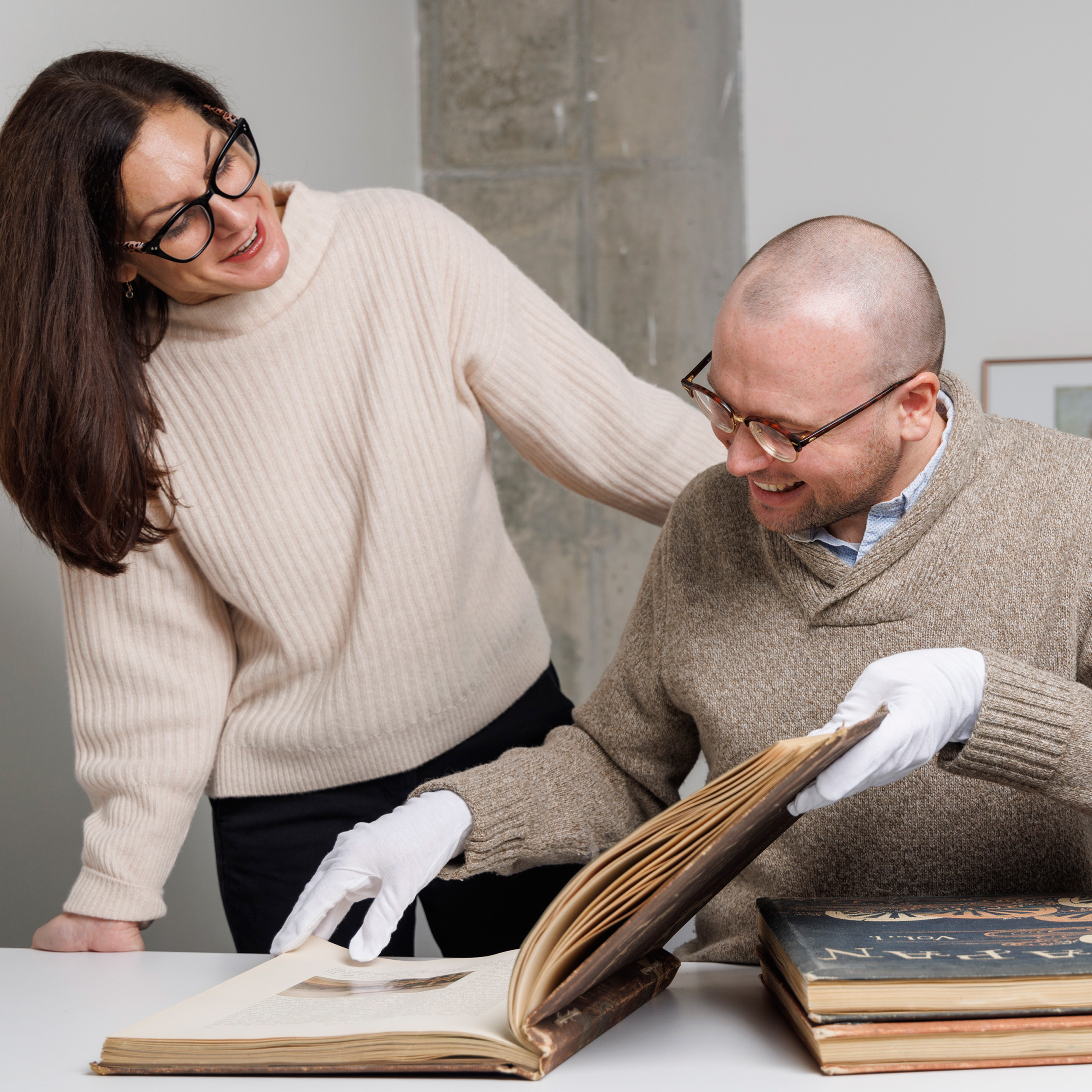 Renée Albiston and MacKenzie Coyle pouring over a large book and research together