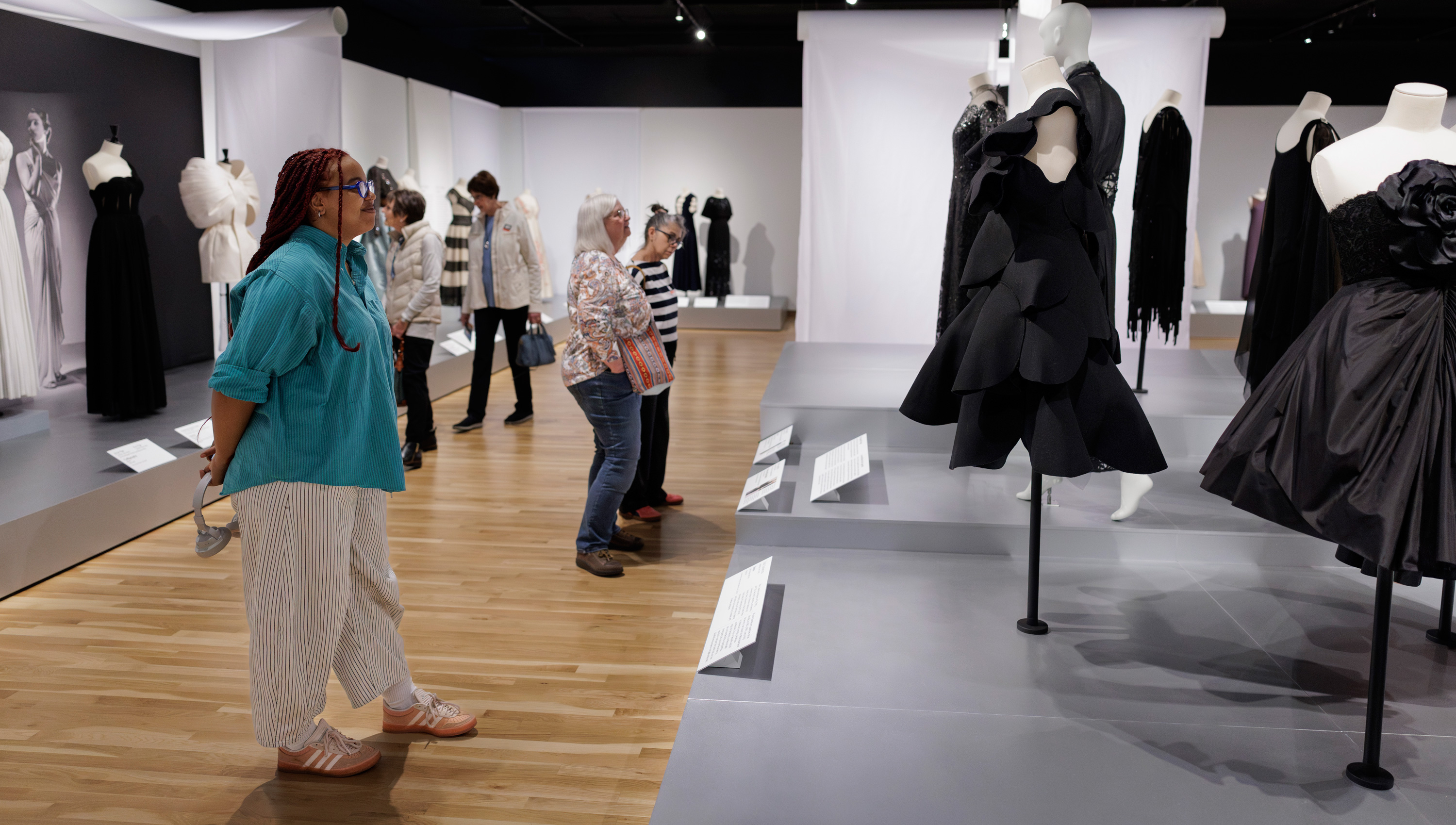 visitors look at dresses in the Conversation Pieces exhibition