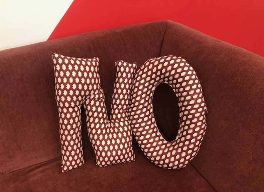 Textile spelling out the word 'no' resting on a couch like a pillow