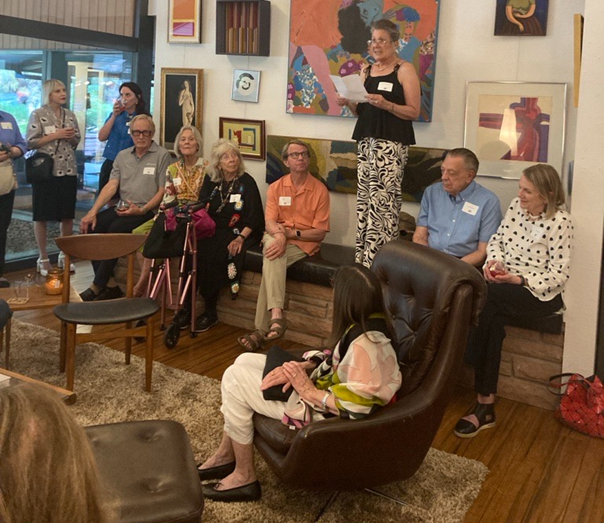 Woman giving a speech in front of visitors in her home
