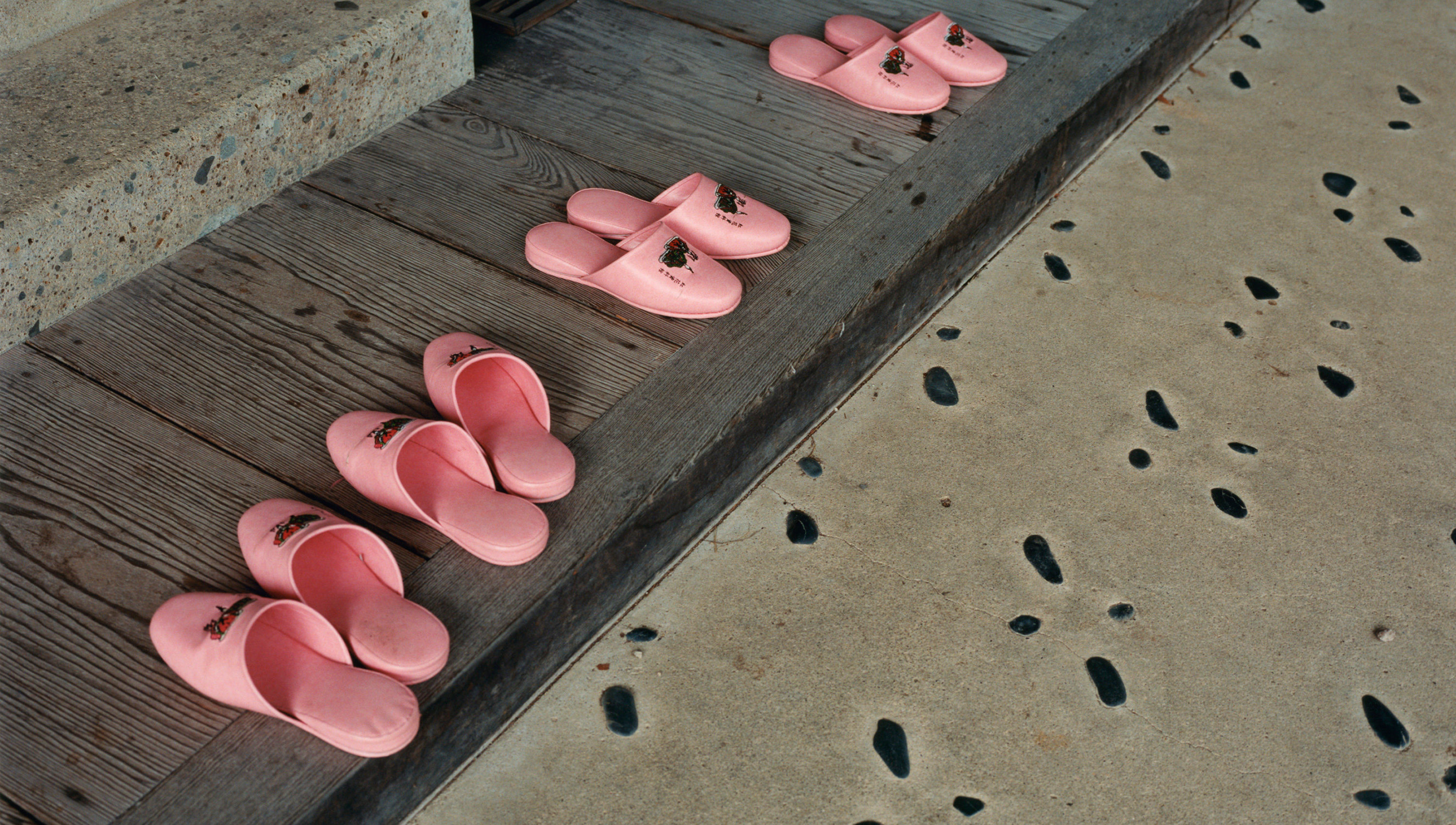 a photo of four pairs of pink slippers on the floor