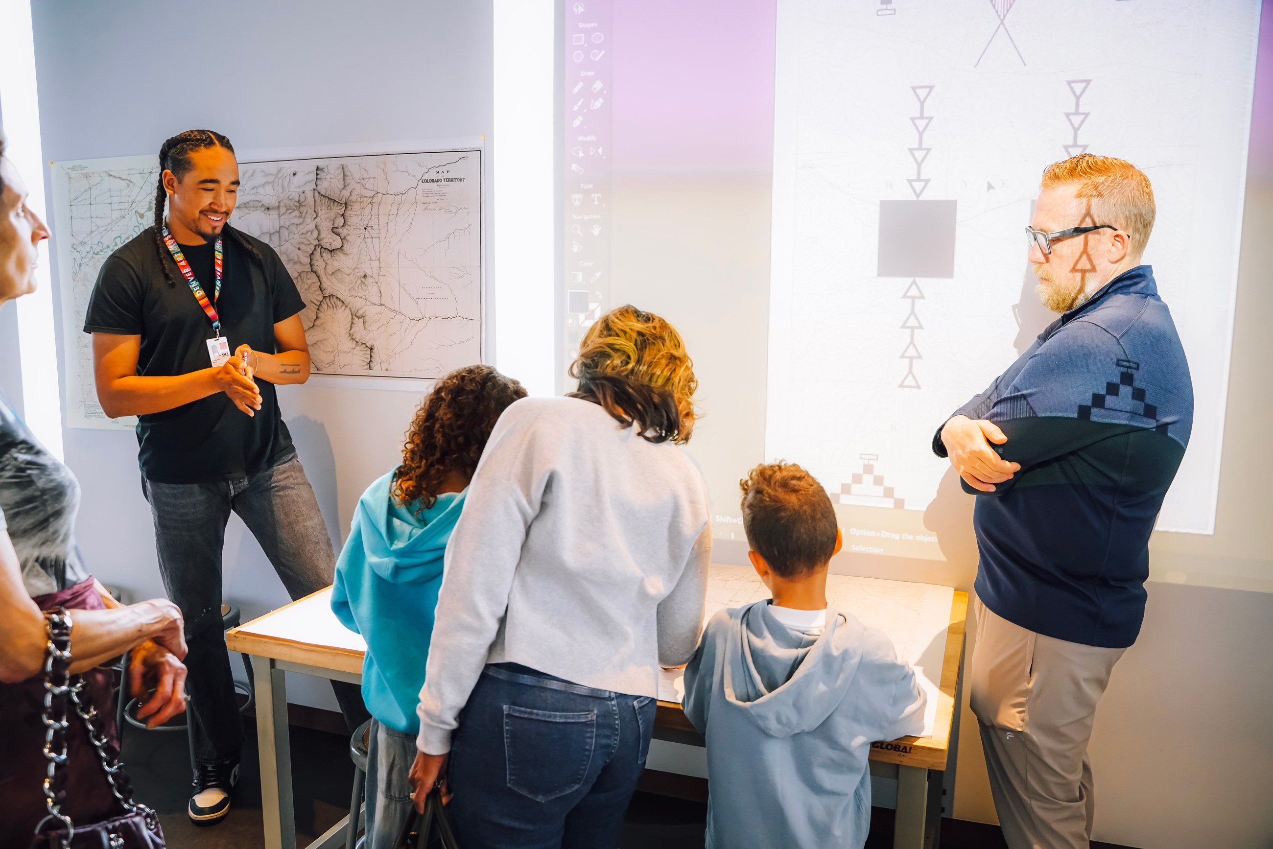 Cooxooeii Black showing his art to a family of four visitors
