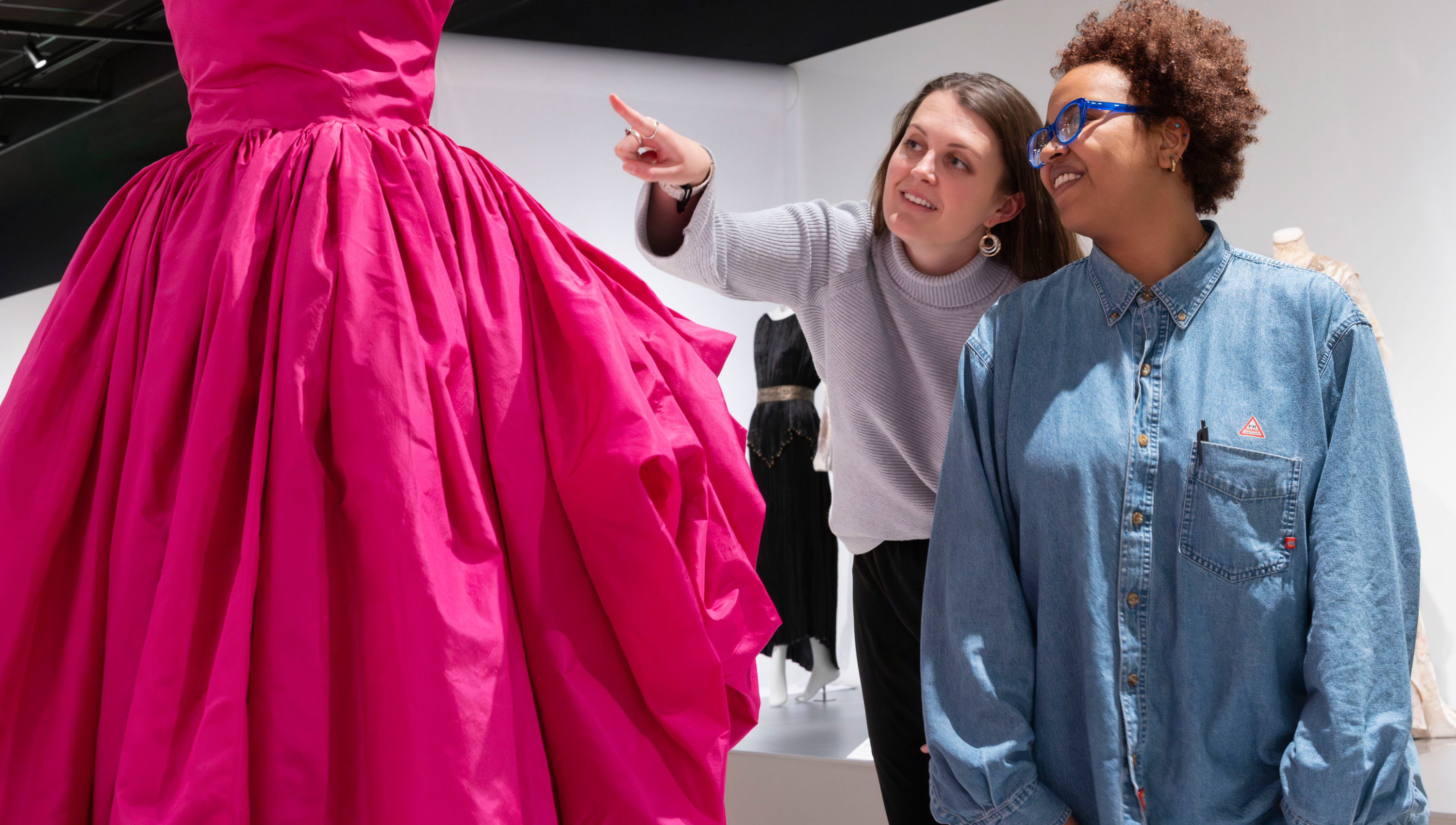 two women looking at a pink dress in the Conversation Pieces exhibition