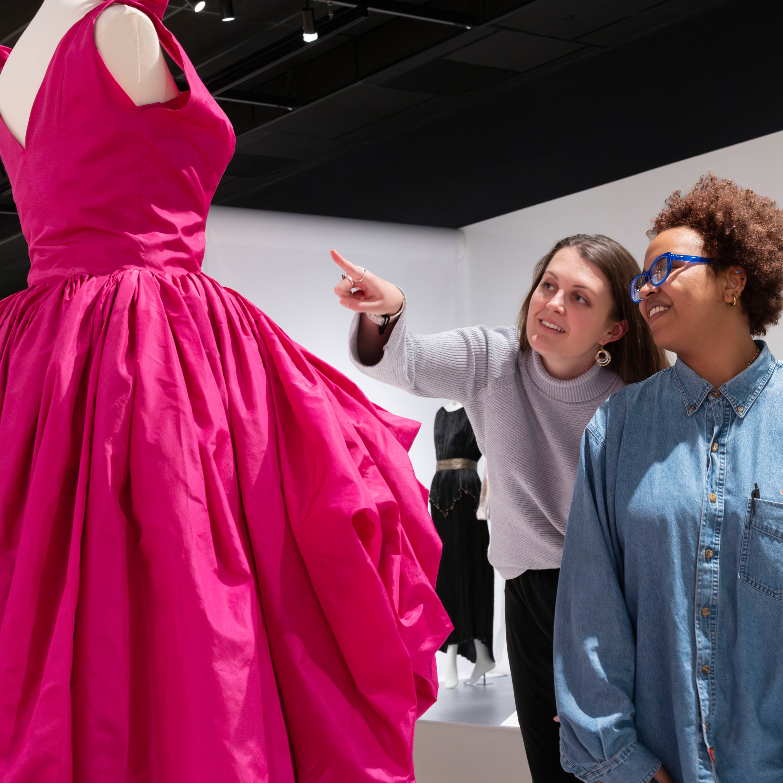 two women looking at a pink dress in the Conversation Pieces exhibition