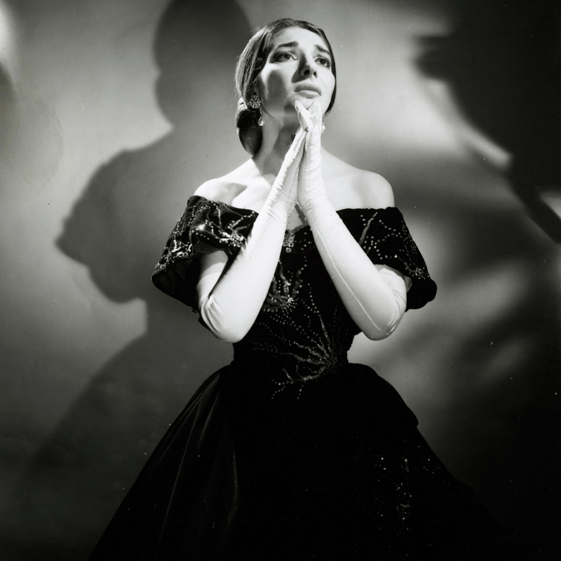 Black and white photograph of opera singer Maria Callas, in an elegant black ball gown