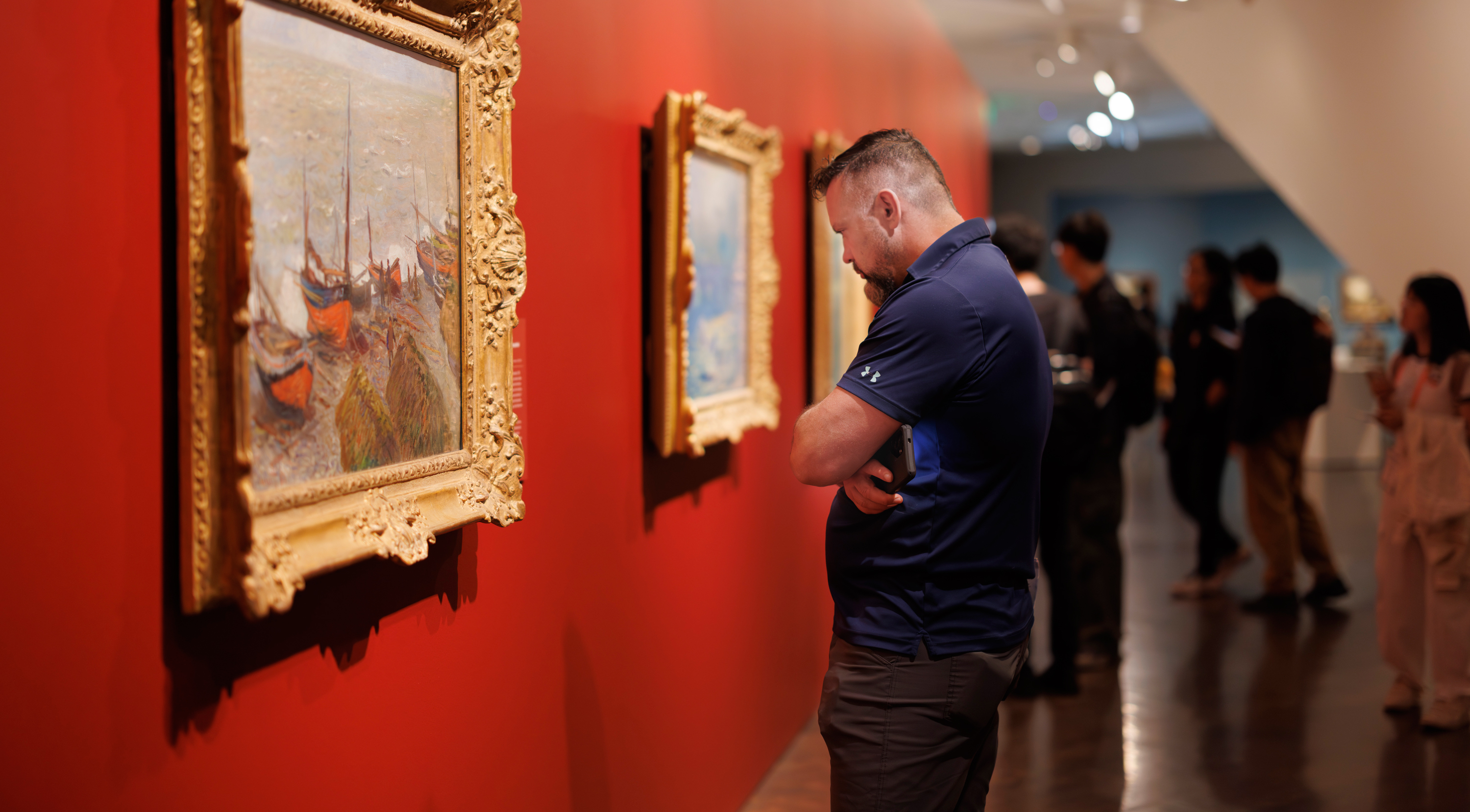 Man reading the label for an Impressionist painting