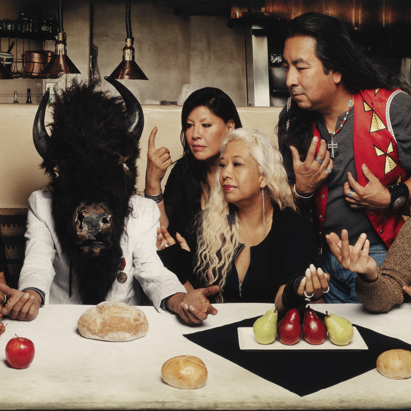 Native Americans gathered around a long horizontal dinner table