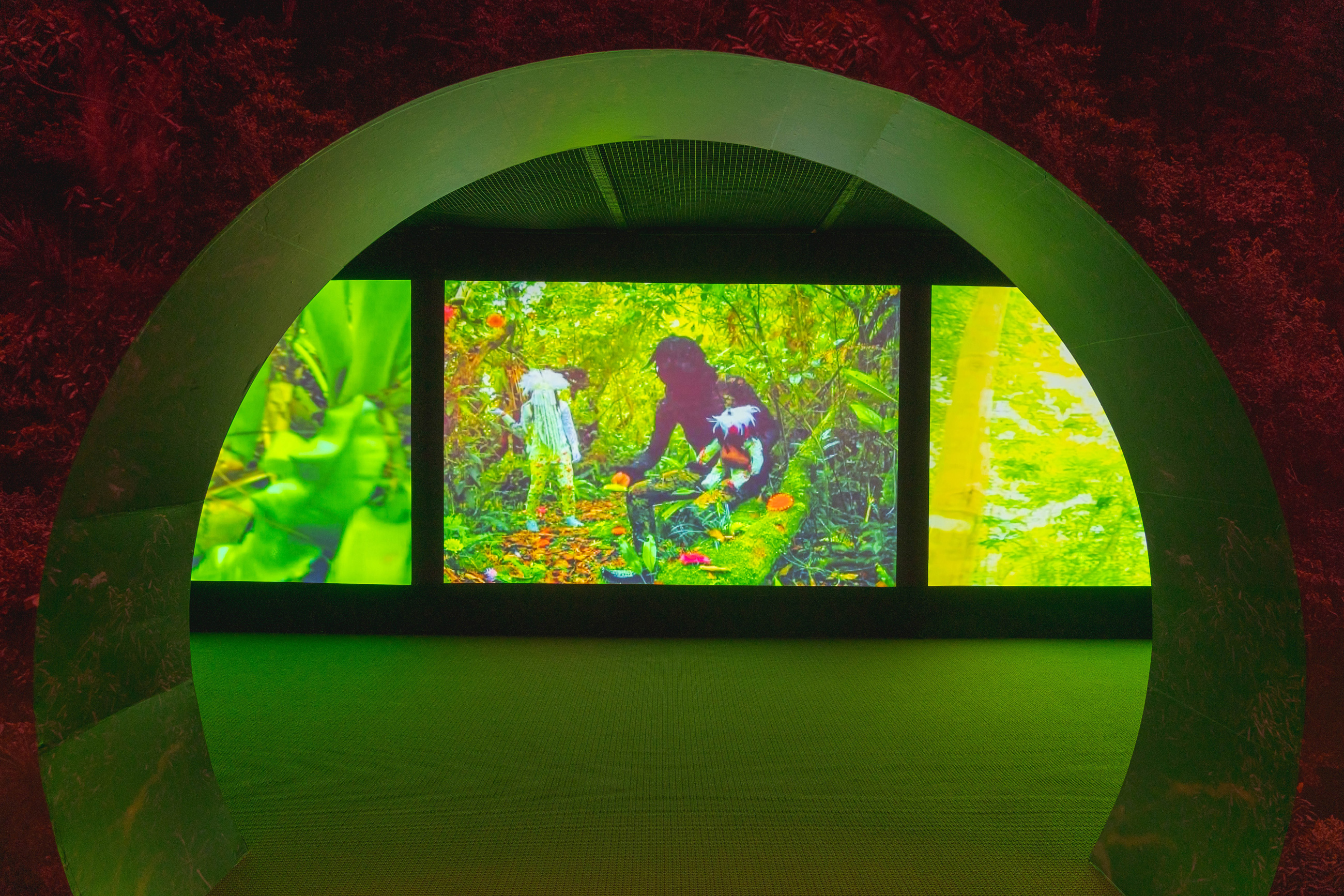 Gallery view of a bright green video installation spanning three separate screens
