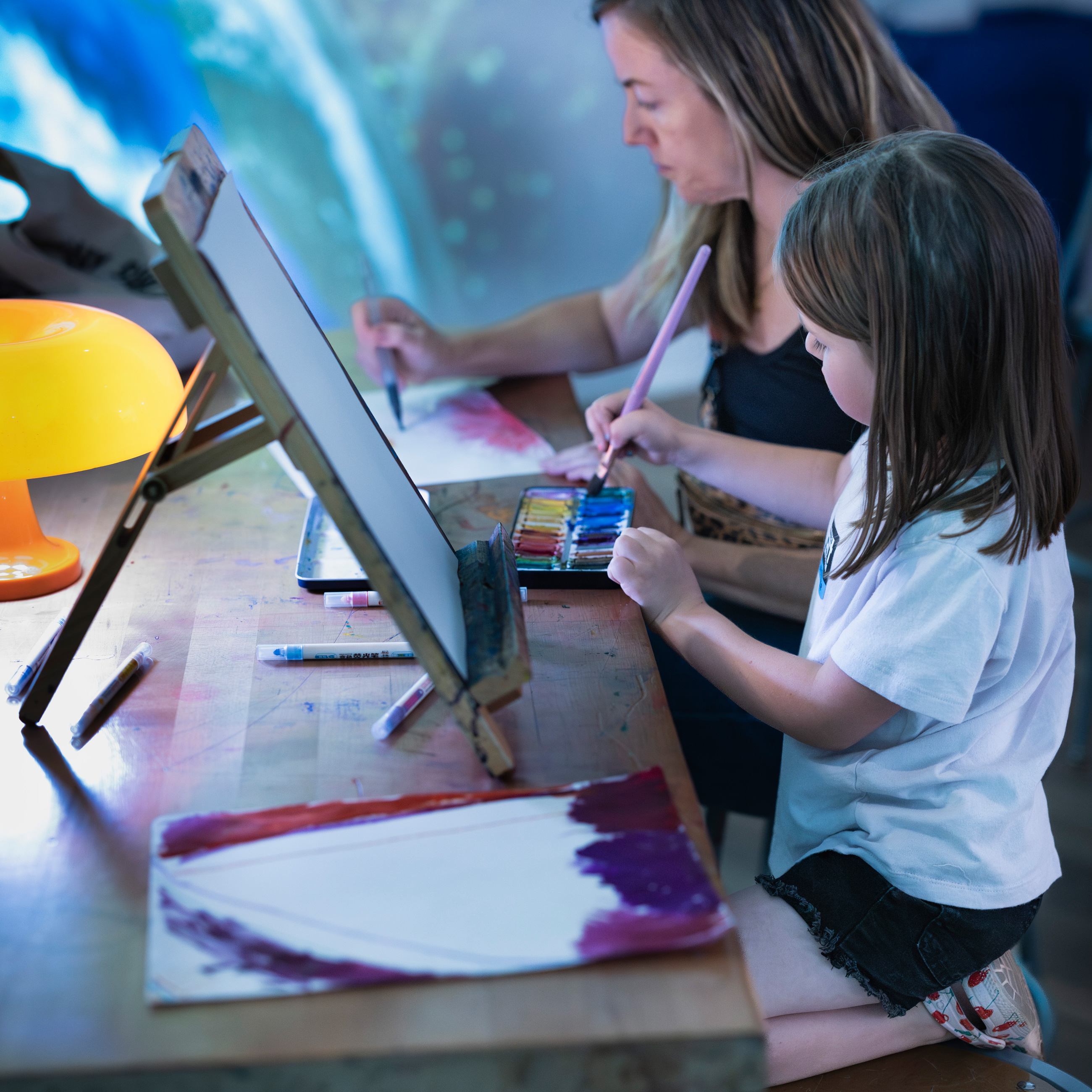 child and parent painting in the cosmic studio