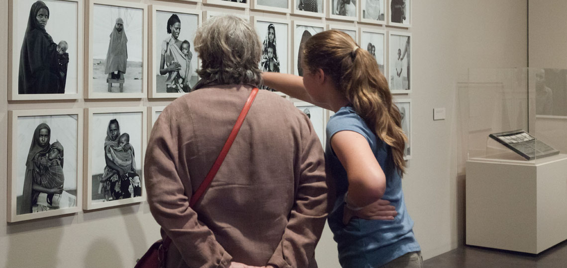 2 women looking at black and white photos by Fazal Sheikh
