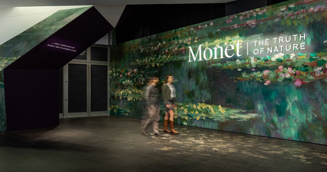A man and a woman in front of the title wall that says Monet The Truth of Nature