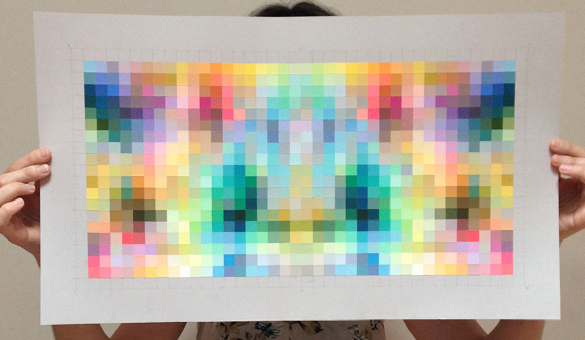 photo of the artist holding up one of her works so you can't see her face; the painting is filled with squares painted different colors
