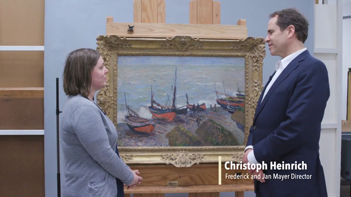 Pam Skiles and Christoph Heinrich standing in front of a painting of fishing boats placed on an easel