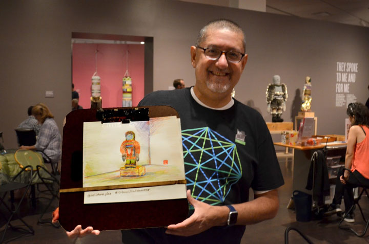 man holding up a man holding a drawing at a drop-in class in the Jeffrey Gibson: Like a Hammer exhibition