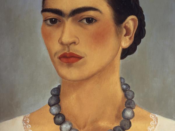 Frida Kahlo from the neck up, wearing a prominent gray beaded necklace