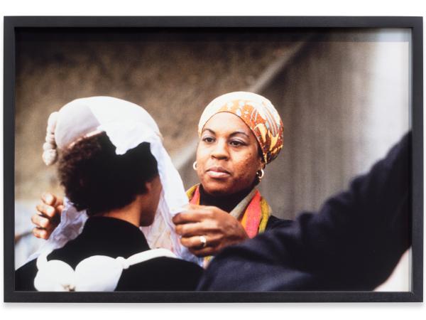 A Black woman placing a sheet over another person