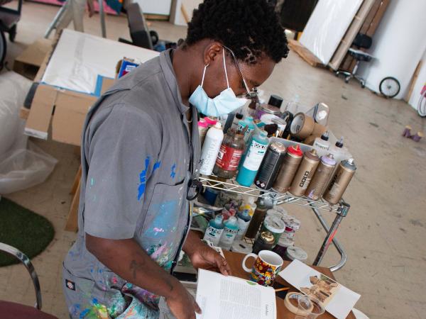 Side view of Simphiwe working in his studio while wearing a mask