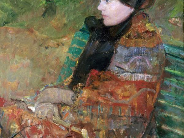 A woman in a coat and warm clothing sitting on a park bench.