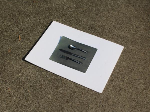 A piece of paper with silver kitchen cutlery at the center