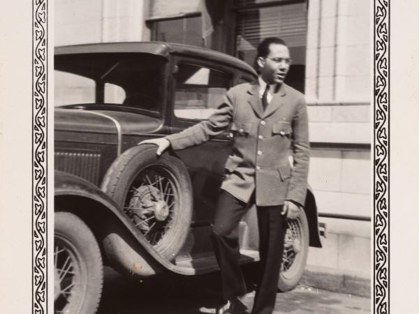 a man in a suit poses near a car