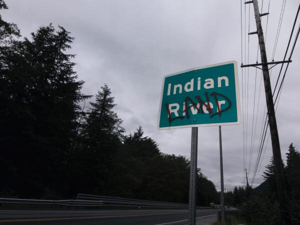 Road sign that reads "Indian River" with the word "land" graffitied over river