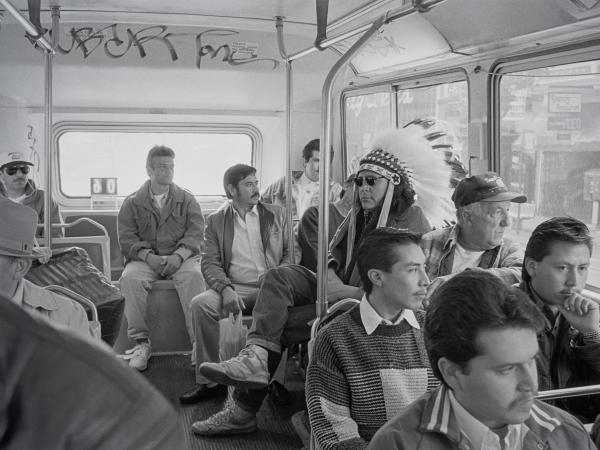 Black and white photograph from the 1950s of a Native American man sitting in a crowded bus