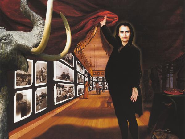 A man holding up a curtain to a gallery filled with photographs, animals, and people