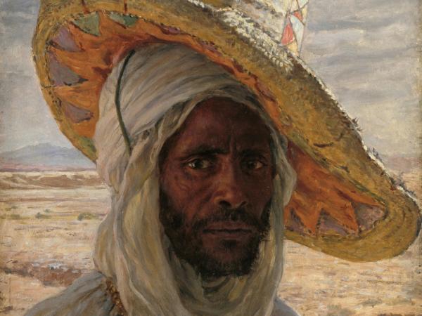 Close-up profile of a man dressed in white with a large straw hat tilted to the side atop his head