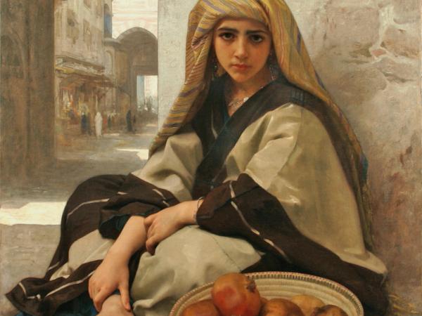 Young woman sitting barefoot on the ground with a basket of pomegranates