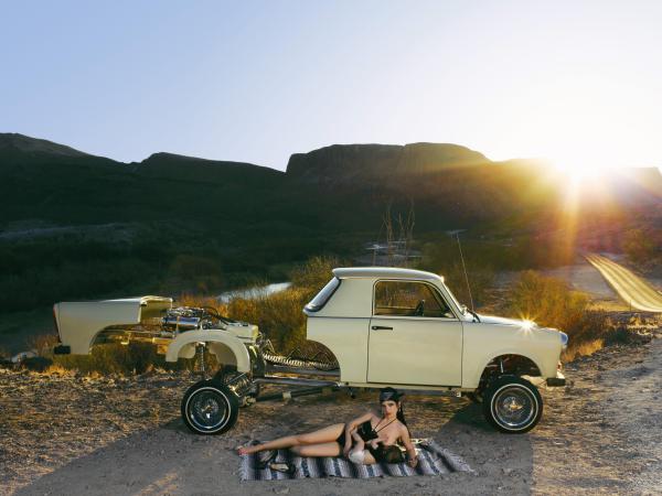 Woman lying in front of a low rider car with her baby 