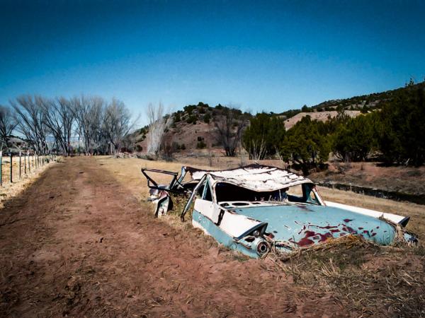 Broken down old white car in a large empty field in New Mexico