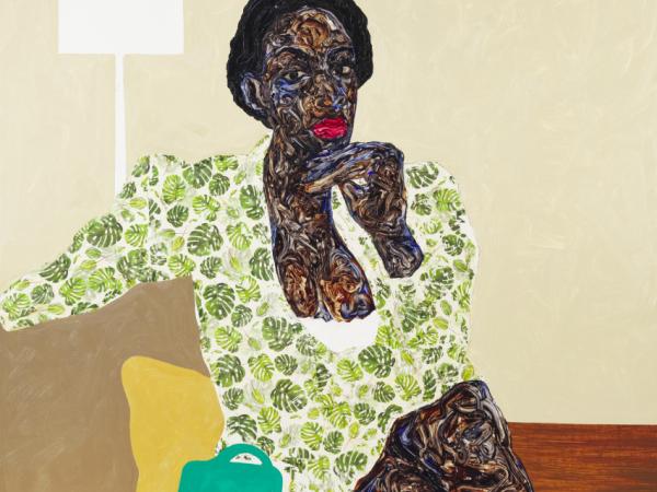 Black woman sitting cross-legged on a couch wearing a green leaf outfit
