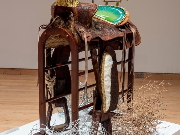 Mixed media installation of a saddle with leather attachments