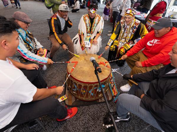 Group of men in a circle performing on a drum