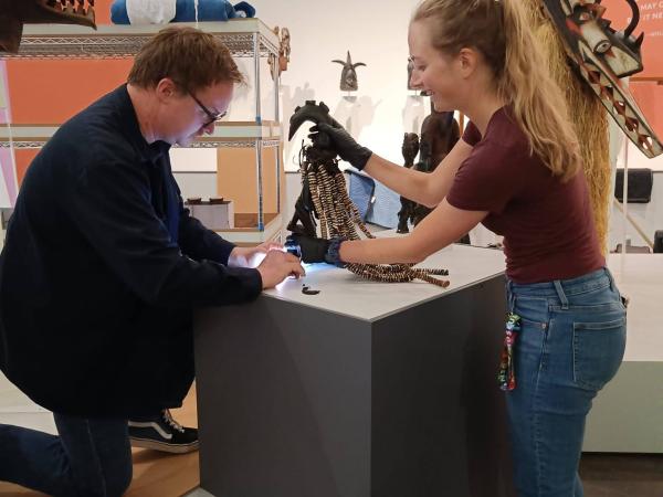 woman and man installing Esu figure in the gallery