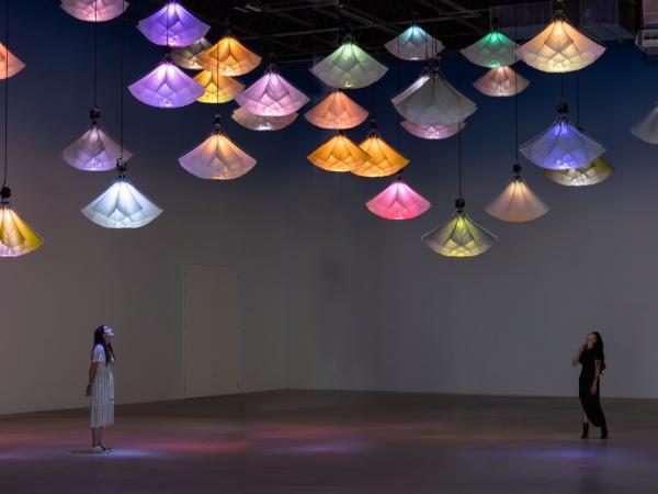 Two visitors looking up at a group of hanging light installations